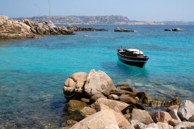 La Maddalena Takımadası 'ndaki turkuaz bir körfeze demir atmış küçük eski bir tekne. Sardunya' ya yolculuk için gidilecek yer.