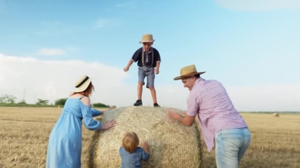 子育ても家族も干し草の上で子供の乗馬を楽しんでいます — ストック動画