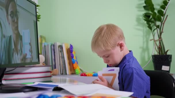 Scolarizzazione a casa bambino, allievo ragazzo con sindrome di Down impara attraverso la comunicazione online con l'insegnante mentre seduto con il computer in camera in tempi coronavirus — Video Stock