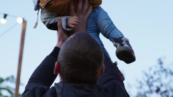 Paternitate, tată iubitor se distrează cu fiul mic în aer liber, băiețel în brațele taților pe fundalul cerului albastru — Videoclip de stoc