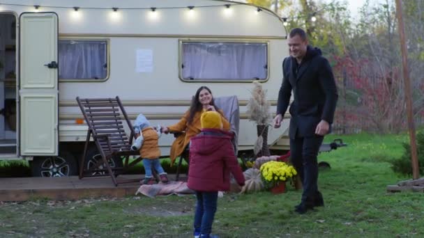 Week-end heureux, famille s'amuser près caravane camping-car, jeune mère avec enfant regarde un père actif courir avec son fils sur la pelouse — Video