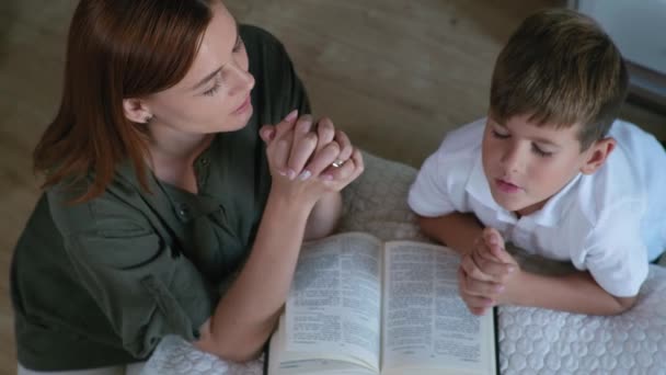 Mère et fils les mains jointes et les yeux fermés avec une foi forte dans leur cœur prient Dieu — Video