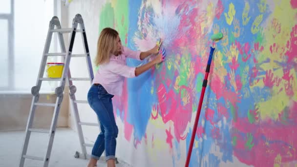 Hand drawing, cheerful young woman actively draws with her fingers with colorful paints on wall at new home — 비디오