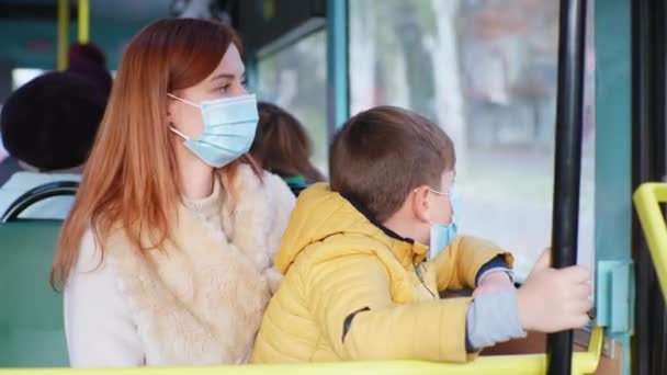 Ridning i kollektivtrafik, ung kvinna och pojke vidta försiktighetsåtgärder på offentlig plats och bära medicinsk mask för att skydda mot virus och infektion när du reser i stadsbuss — Stockvideo