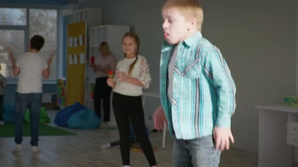 Aktiver Junge mit Down-Syndrom springt aktiv auf Trampolin und hat Spaß drinnen, Leben mit Behinderungen — Stockvideo