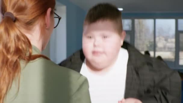 Tlustý chlapeček s Downovým syndromem aktivně skákat na trampolíně držet se za ruce učitelky, bezstarostné a aktivní dětství — Stock video