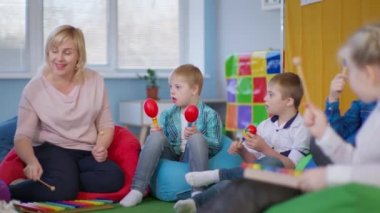 Down sendromlu çocuklar müzik öğretmenini dikkatle dinleyin, müzik aletleri olan çocuklar çok renkli fasulye koltuklarına oturun.