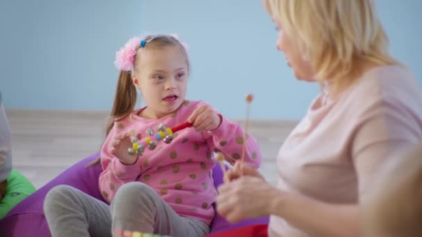Dítě s Downovým syndromem těší hudební lekce ve třídě se svým učitelem, žena s xylofonem naučit dívku hrát s zvony — Stock video