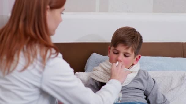 Mutter kümmert sich um die Gesundheit ihrer Söhne und träufelt Nasentropfen von einer Erkältung — Stockvideo