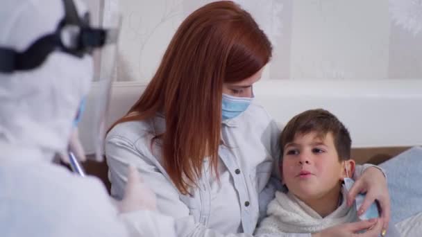 Kendini kötü hisseden çocuk, virüs ve enfeksiyondan korunmak için koruyucu giysili sağlık uzmanına beş puan verdi. — Stok video