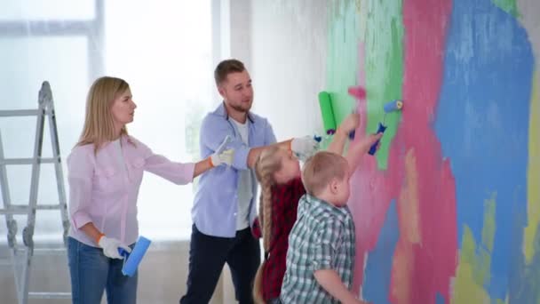 Parents profiter du temps avec la fille et le garçon avec le syndrome du duvet peinture murs avec des peintures colorées — Video