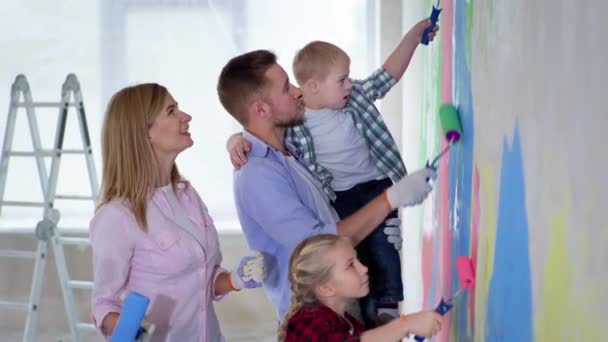 Famille avec fille et garçon avec le syndrome du duvet peinture murs avec des peintures colorées à l'aide de rouleaux de construction dans le nouvel appartement — Video