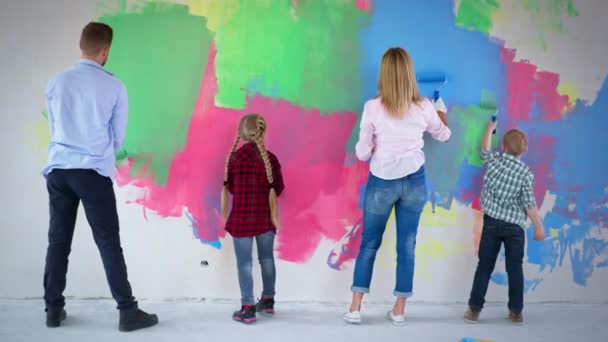 Mężczyzna i kobieta z zespołem Downa dziewczyna i chłopiec malowanie ścian w różnych kolorach za pomocą walców budowlanych — Wideo stockowe