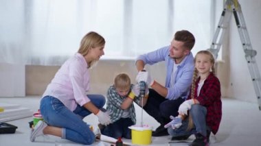 Down sendromlu çocuklu bir aile yenileme sırasında duvarları boyamak için pigmentleri karıştırıyor.