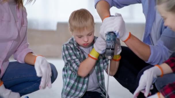 Bambino maschio con sindrome di Down versa pigmento rosso in vernice e si mescola con trapano da costruzione mentre aiuta la sua famiglia — Video Stock