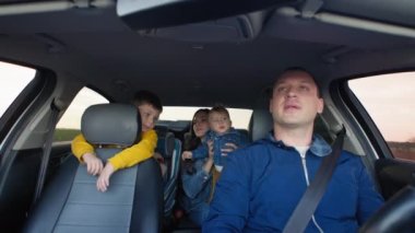 Çocuklarla yolculuk, aile babası arka koltukta eş, küçük erkek çocuk ve oğlu araba koltuğunda.