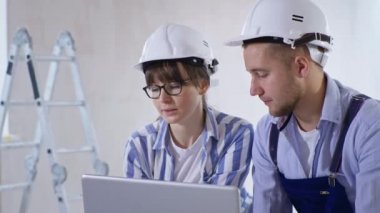 Renk paleti tutan kasklı profesyoneller duvar yenileme, onarım ve dekorasyon sırasında yeni oda tasarımını tartışıyorlar