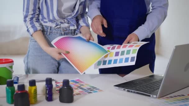 L laki-laki dan perempuan tim renovasi memilih cat dari palet warna untuk dinding dalam ruangan pekerja konstruksi, close-up — Stok Video