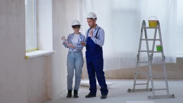 Costruttori maschili e femminili in caschi di sicurezza scegliere nuovi disegni parete dalla tavolozza dei colori — Video Stock