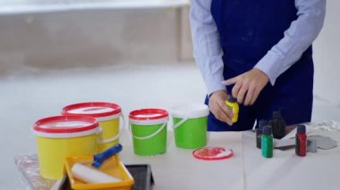 Erkek müteahhit inşaat alanını yenilemek için boyaya sarı boya döküyor.