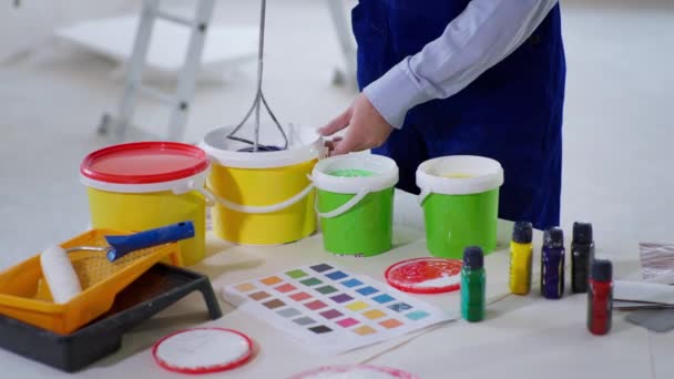 Hombre trabajador de la construcción mezcla de pintura con pigmento de color de construcción batidor para la pintura de pared — Vídeos de Stock