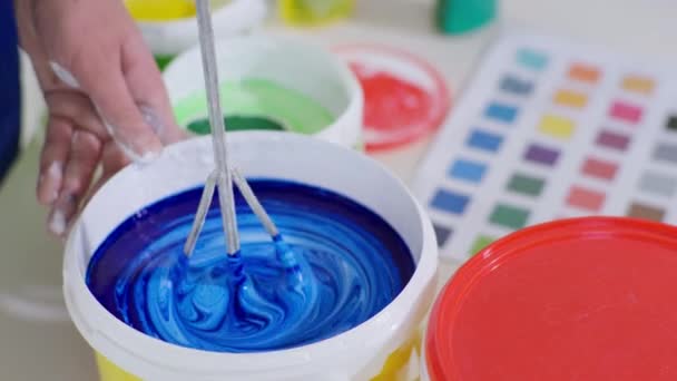 Construtor mistura pigmento azul com tinta branca em balde com batedor de construção e broca para pintar paredes — Vídeo de Stock