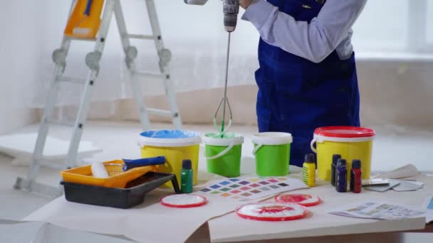 Peintre masculin mélange la peinture dans le seau avec mélangeur de construction pour la peinture des murs à l'intérieur — Video