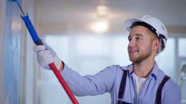 남자 도화가는 실내 수리 나장 식품을 할 때 손으로 롤러 브러시를 사용하여 벽을 페인트 한다 — 비디오