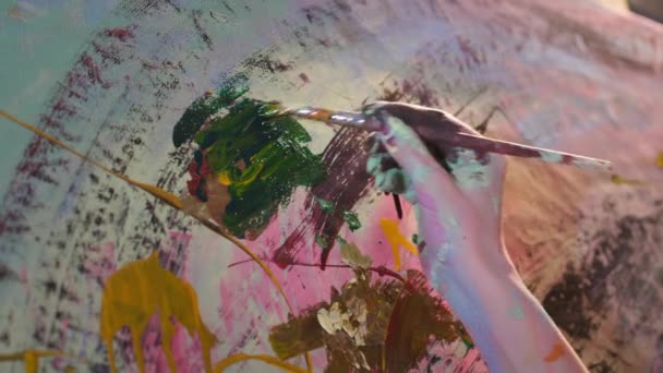 Ruce umělce štětcem malovat obraz na plátno, detailní záběr na ruce potřísněné barvami v procesu kreativity ve studiu — Stock video