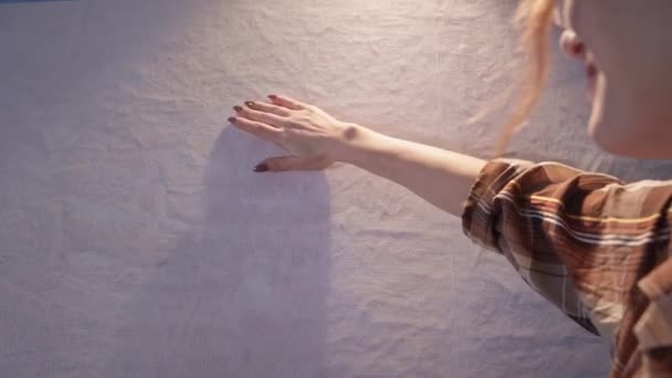 Usmívající se umělec stojí u stojanu před kresbou, žena ruka hladí prázdné plátno s osvětlením v dílně — Stock video