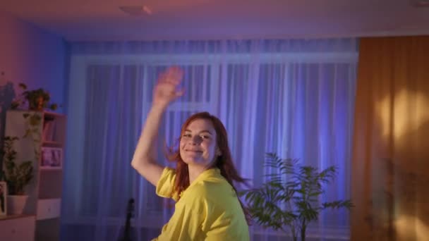 Kvinna som har roligt och dansar i rummet på natten, tittar på kameran — Stockvideo