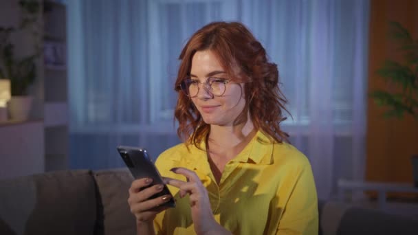 ผู้หญิงที่มีแว่นตาใช้โทรศัพท์มือถือเพื่อซื้อสินค้าบนอินเทอร์เน็ตยิ้มและแสดงนิ้วโป้งขึ้น — วีดีโอสต็อก
