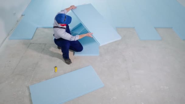 Bauarbeiter legt Styropor aus, um Platz für Laminatboden auf Baustelle zu schaffen — Stockvideo