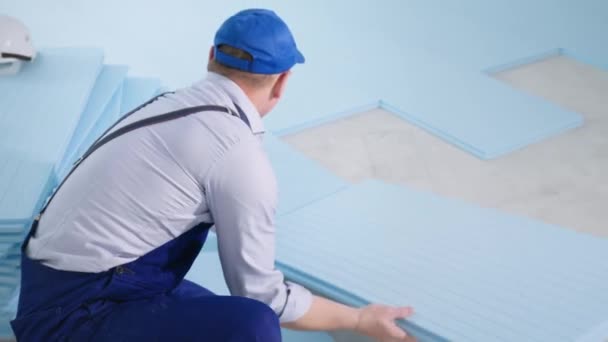 建筑公司穿着特殊服装的男性员工在室内铺设保温层和层压板用聚苯乙烯泡沫 — 图库视频影像