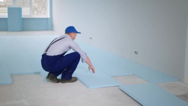 Renovação de instalações, jovem em roupas de trabalho piso isolado com poliestireno expandido antes de colocar laminado no chão — Vídeo de Stock