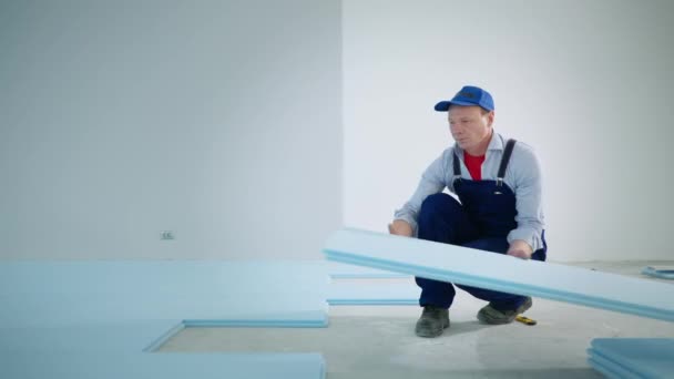 Retrato construtor masculino executa trabalhos de construção isolar piso com espuma de poliuretano antes de colocar laminado dentro de casa — Vídeo de Stock