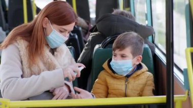 Anne, çocuğun sağlığıyla ilgilenecek ve tıbbi bir maske takacak ve otobüste ellerini antiseptikle tedavi edecek.
