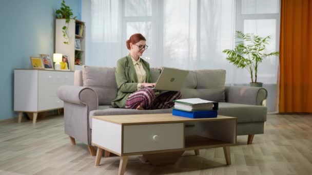 Kobieta w kurtce i spodnie piżamy z laptopem pracuje w domu podczas kwarantanny i samoizolacji — Wideo stockowe