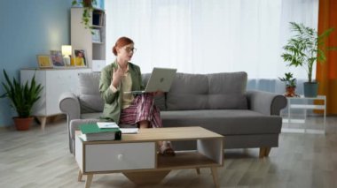 Ceketli ve pijamalı bir iş kadını, karantina sırasında evdeki kanepede otururken bilgisayardan bilgisayar başında video görüşmeleri yapıyor.