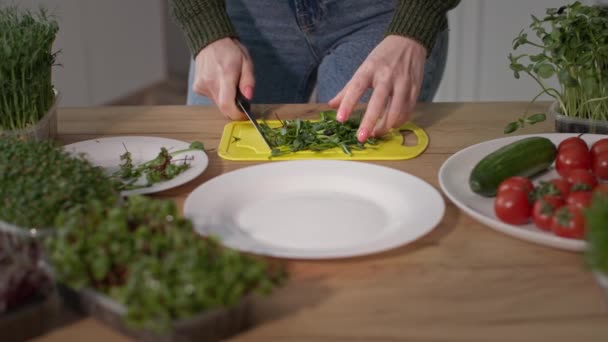 Sommar uppfriskande vegetarisk sallad, flicka skär mikrogröna och körsbärstomater med kniv på en skärbräda i köket — Stockvideo