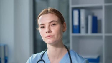 Kameraya bakan yorgun doktor portresi, steteskoplu mavi üniformalı kadın terapist bilgisayar monitöründe zor bir günün ardından gözlüklerini çıkarıyor.