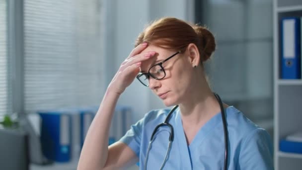 Portrait de femme surmenée enlève des lunettes et regarde la caméra, femme fatiguée médecin se sent mal à la tête tout en travaillant à un ordinateur à l'hôpital — Video