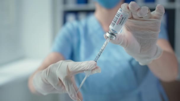 Maskierter Arzt hält Spritze und Impfflasche im Krankenhaus, Hände in Schutzhandschuhen — Stockvideo
