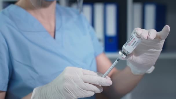 Cauvid 19 aşısı yakın plan, doktor koruyucu eldivenleri şırıngayla veriyor cam ampulün lastik mührünü deliyor ve ilacı alıyor. — Stok video