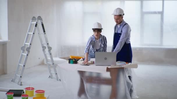 Laki-laki dan perempuan konstruksi profesional memilih warna cat dari warna swatch saat mengecat dinding — Stok Video