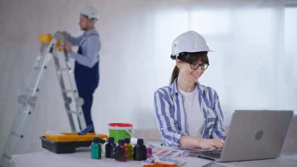 Wanita cantik yang bekerja sebagai desainer interior memilih warna cat untuk dinding sambil duduk di komputer — Stok Video