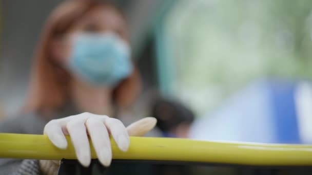 Passageira do sexo feminino no ônibus da cidade vestindo luva médica para proteger contra vírus e infecção segura para corrimão enquanto viaja em transportes públicos, close-up — Vídeo de Stock