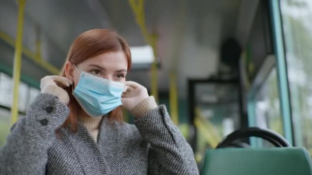 Női utas visel orvosi maszkot, hogy megvédje a koronavírus fertőzés, és megragadja a korlátot, miközben lovagol városi busz — Stock videók
