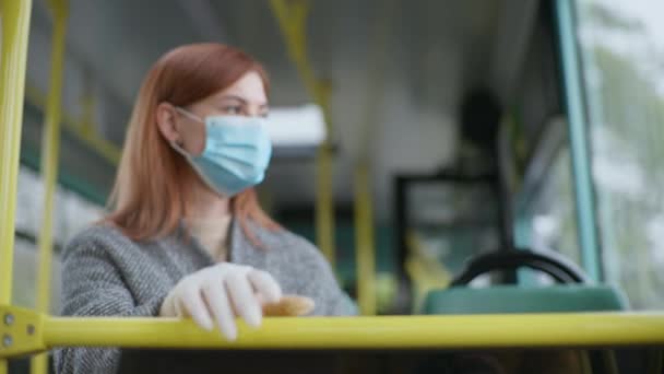 Wanita bertopeng medis dan sarung tangan mengobati tangan dengan antiseptik untuk mensterilkan dari virus dan infeksi dan meletakkan tangannya di pegangan selama perjalanan di depan umum — Stok Video