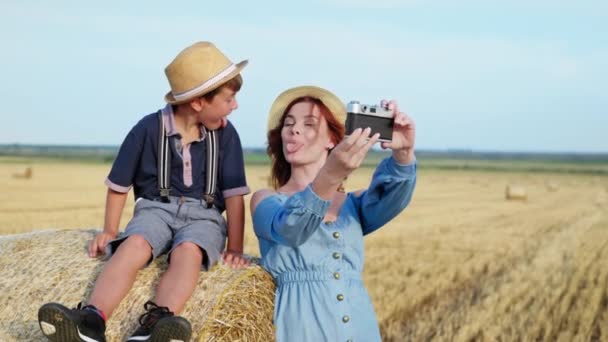 Žena se svým synem baví ukazovat jazyky k sobě a jsou fotografovány na retro fotoaparátu — Stock video